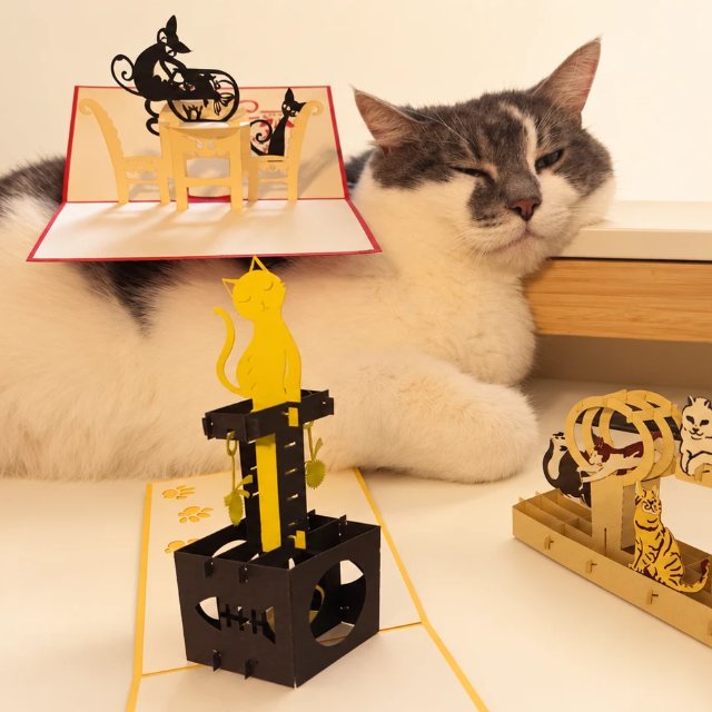 Mikko-kissa poseeraa 3D pop-up-kortin kanssa – Kovassa työssä